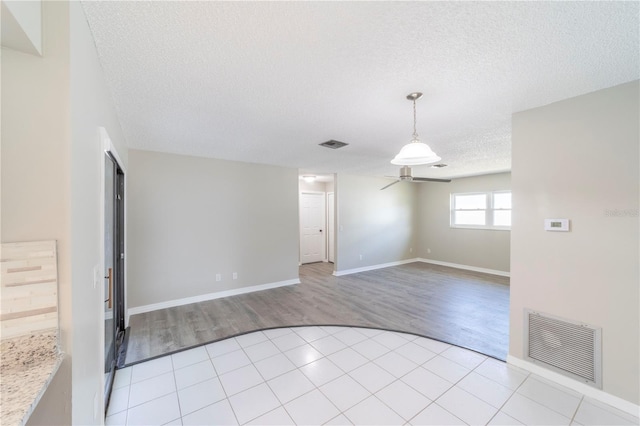 spare room with baseboards, visible vents, a textured ceiling, and light tile patterned flooring