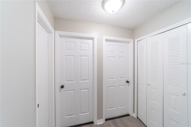 hall with a textured ceiling and light wood-type flooring