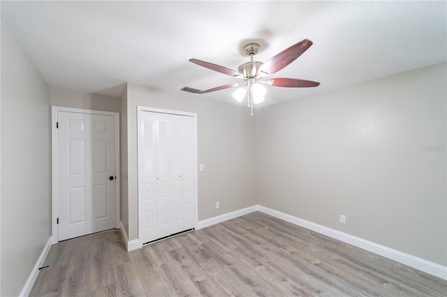 unfurnished bedroom with ceiling fan, visible vents, baseboards, light wood-style floors, and a closet