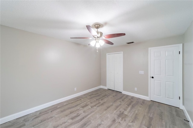 unfurnished bedroom with visible vents, baseboards, light wood-style flooring, ceiling fan, and a closet