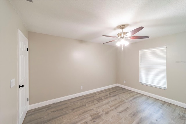 spare room featuring baseboards, a textured ceiling, a ceiling fan, and light wood-style floors