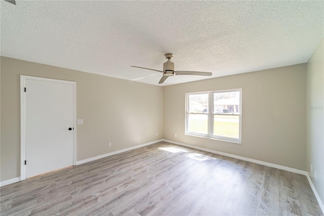 empty room featuring light wood-style flooring, baseboards, ceiling fan, and a textured ceiling