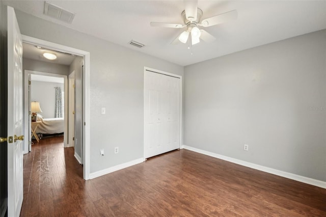 unfurnished bedroom with baseboards, a closet, visible vents, and dark wood-style flooring