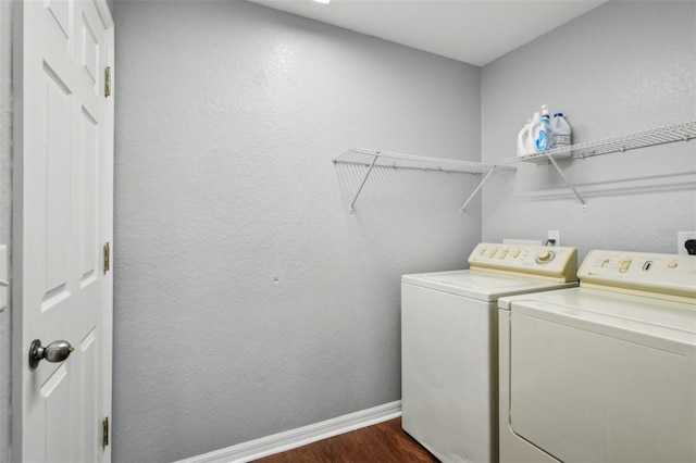 laundry area featuring a textured wall, washing machine and dryer, laundry area, dark wood-type flooring, and baseboards