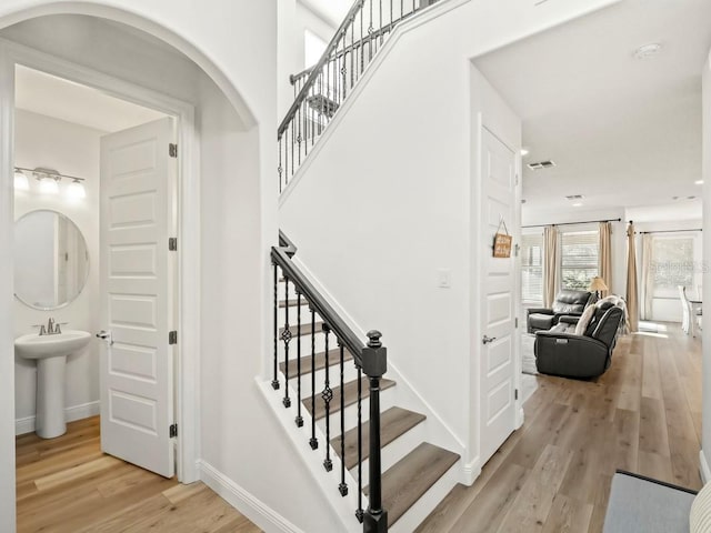 stairs with wood finished floors, a towering ceiling, and baseboards