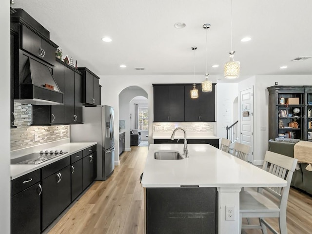 kitchen featuring light countertops, hanging light fixtures, a sink, dark cabinetry, and black electric cooktop