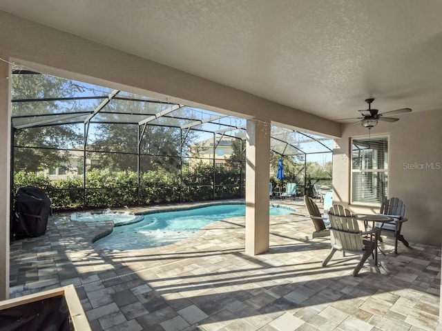 view of pool featuring ceiling fan, glass enclosure, a patio area, and a pool with connected hot tub