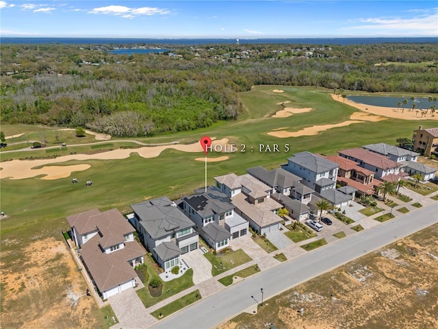 drone / aerial view featuring golf course view, a forest view, a water view, and a residential view