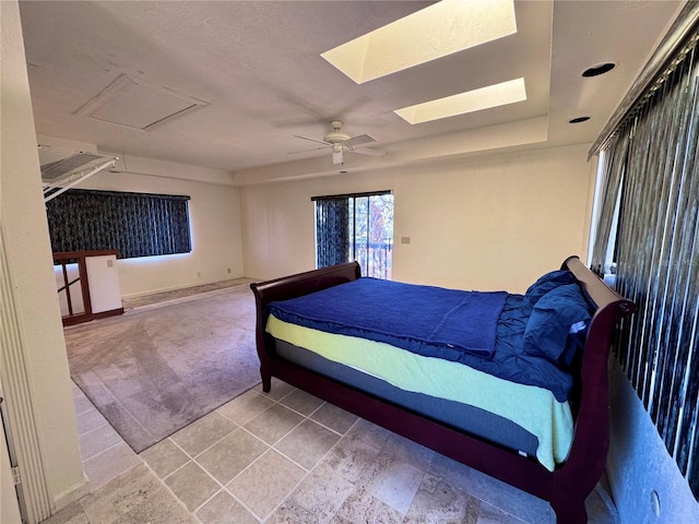 unfurnished bedroom featuring carpet floors, a skylight, a ceiling fan, baseboards, and access to outside