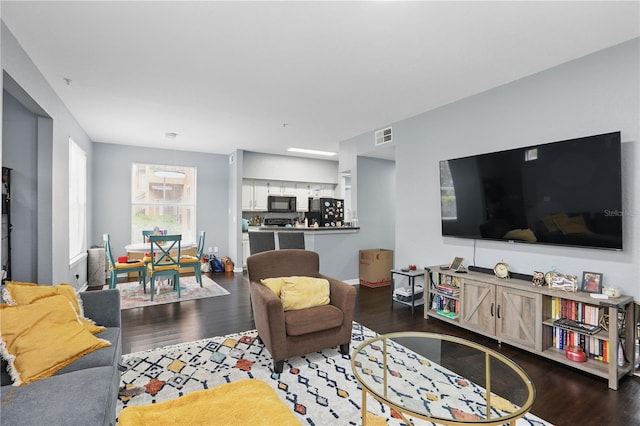 living room featuring visible vents, baseboards, and wood finished floors