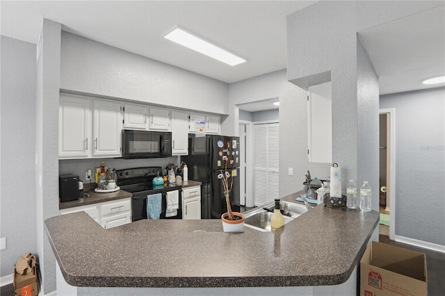 kitchen featuring dark countertops, white cabinets, a sink, a peninsula, and black appliances