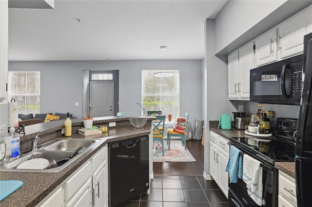 kitchen with dark countertops, black appliances, a wealth of natural light, and a sink