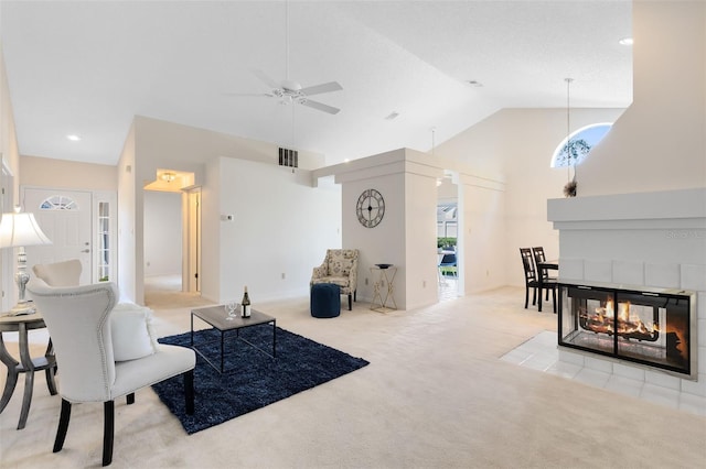 living room with a ceiling fan, visible vents, high vaulted ceiling, a multi sided fireplace, and carpet flooring