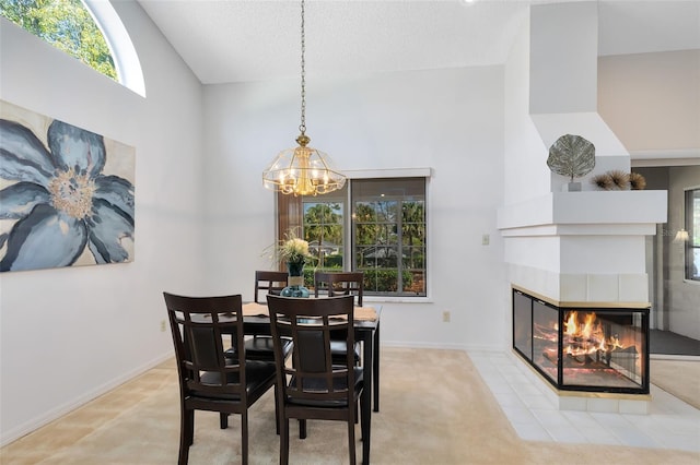 dining space with a tiled fireplace, high vaulted ceiling, baseboards, and a chandelier