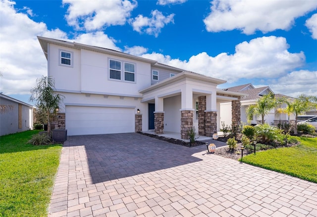 view of front of home featuring decorative driveway, stucco siding, a front yard, a garage, and stone siding