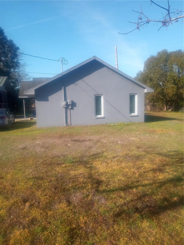 view of side of home with a yard and stucco siding