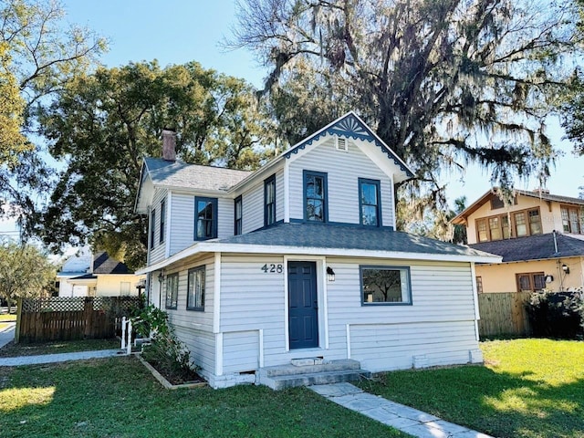 view of front of property featuring a chimney, fence, and a front yard