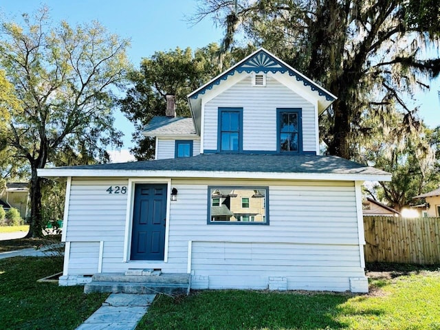 view of front facade featuring a chimney, fence, and a front lawn