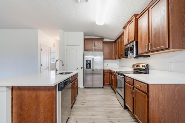 kitchen featuring a sink, light countertops, appliances with stainless steel finishes, brown cabinetry, and an island with sink