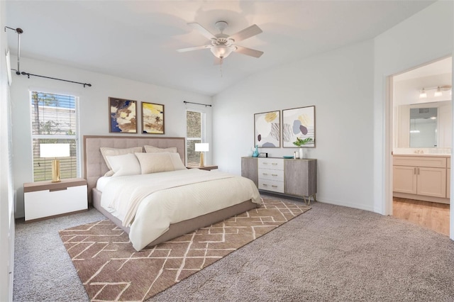 carpeted bedroom with baseboards, a ceiling fan, vaulted ceiling, and connected bathroom