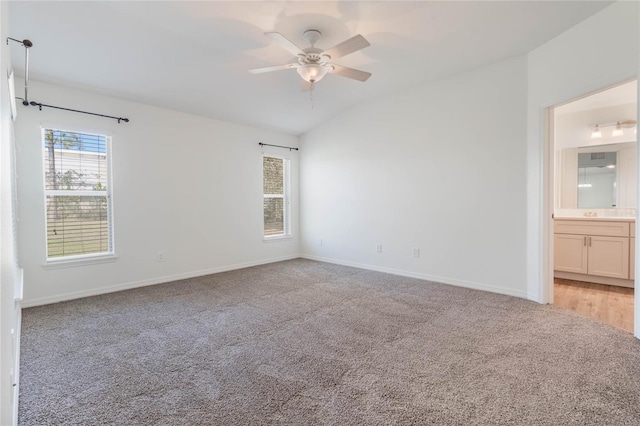 spare room featuring light carpet, ceiling fan, lofted ceiling, and baseboards