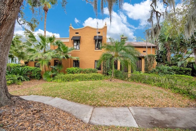 view of front facade with a chimney, a front lawn, and stucco siding