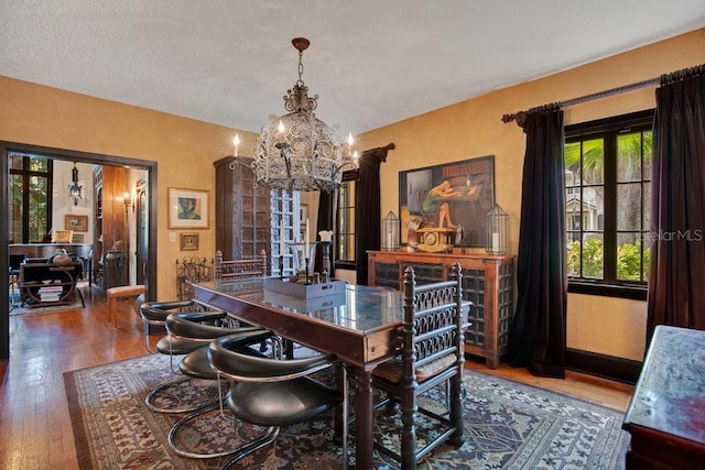 dining room featuring a textured ceiling, hardwood / wood-style floors, and a notable chandelier