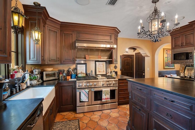 kitchen featuring arched walkways, stainless steel appliances, dark countertops, and under cabinet range hood