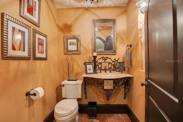 half bath with a sink, toilet, and baseboards