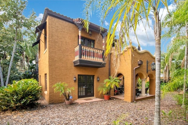 back of house with a patio, french doors, a balcony, and stucco siding