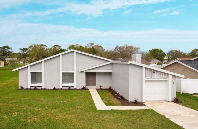 view of front of house with a chimney, an attached garage, fence, driveway, and a front lawn