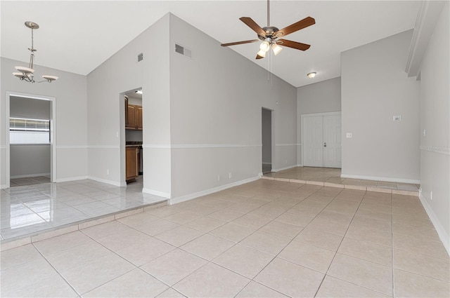 unfurnished room featuring light tile patterned floors, baseboards, visible vents, high vaulted ceiling, and ceiling fan with notable chandelier