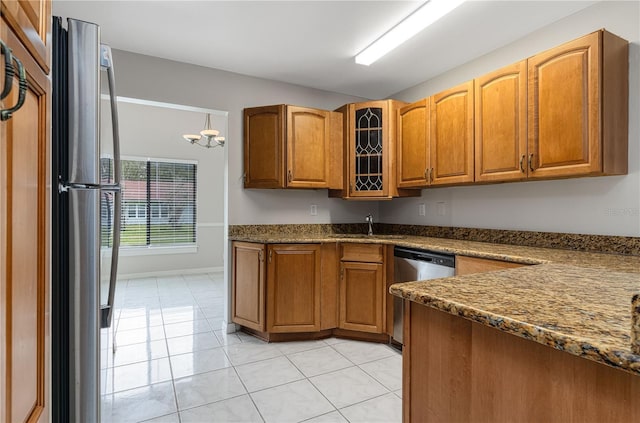 kitchen featuring light tile patterned floors, appliances with stainless steel finishes, brown cabinetry, and a sink