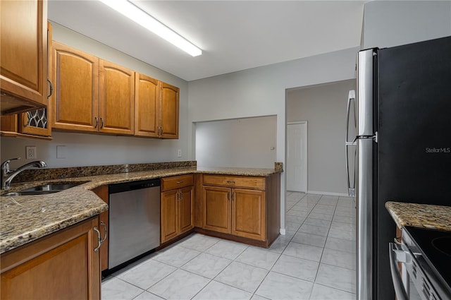 kitchen featuring stone countertops, appliances with stainless steel finishes, brown cabinetry, and a sink