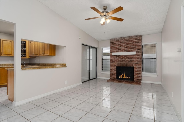 unfurnished living room with ceiling fan, a textured ceiling, light tile patterned flooring, a fireplace, and vaulted ceiling