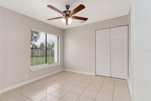 unfurnished bedroom featuring light tile patterned floors, baseboards, visible vents, ceiling fan, and a closet