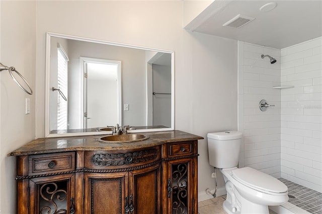 full bathroom featuring toilet, visible vents, a tile shower, and vanity