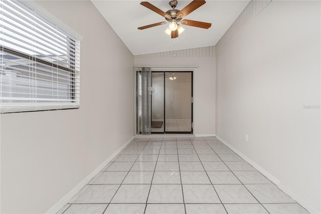 empty room featuring lofted ceiling, baseboards, a ceiling fan, and light tile patterned flooring