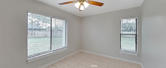 empty room with a ceiling fan, a wealth of natural light, and baseboards