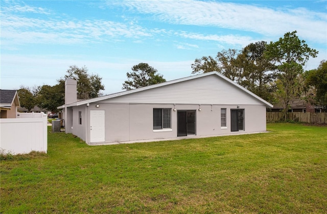 rear view of property with a yard, a chimney, and fence