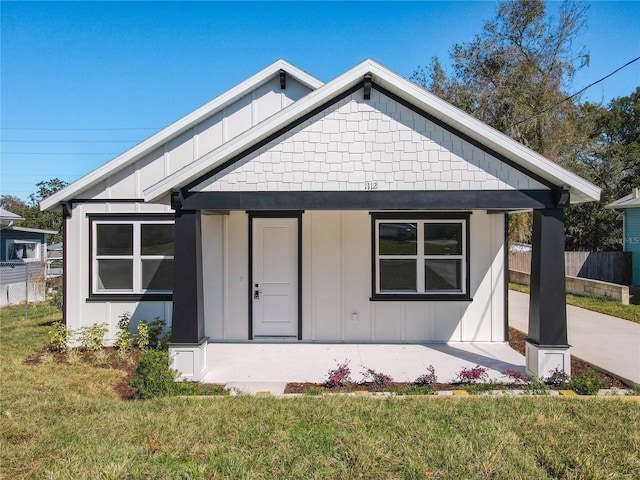 bungalow-style house with fence, a porch, board and batten siding, and a front yard