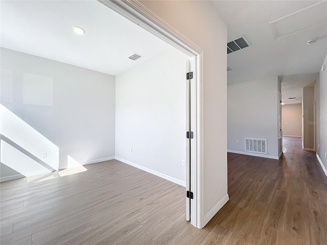 empty room featuring baseboards, visible vents, and wood finished floors