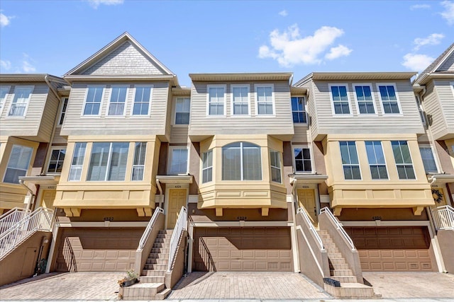 townhome / multi-family property with decorative driveway, an attached garage, and stairs