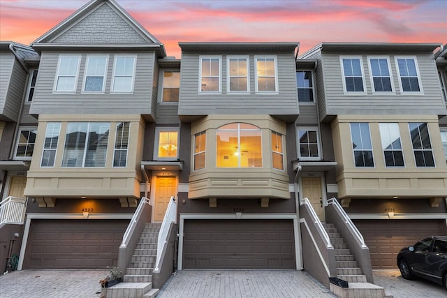 multi unit property featuring decorative driveway, stairway, and an attached garage