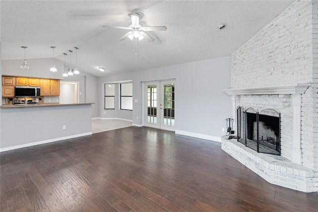 unfurnished living room with baseboards, lofted ceiling, wood finished floors, french doors, and a fireplace