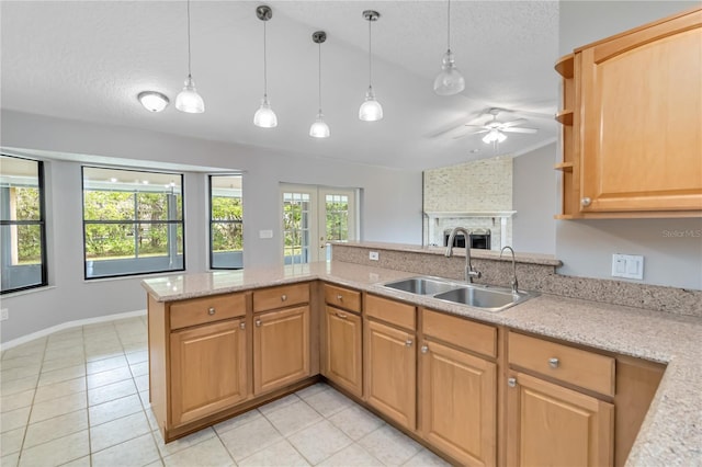 kitchen featuring a textured ceiling, a peninsula, a fireplace, a sink, and hanging light fixtures