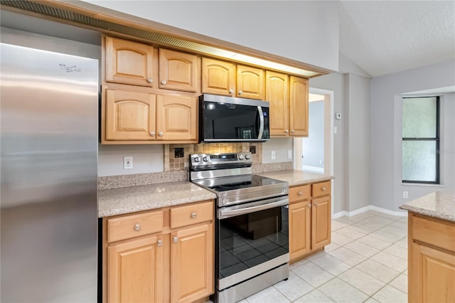 kitchen with lofted ceiling, stainless steel appliances, light brown cabinets, and light stone countertops