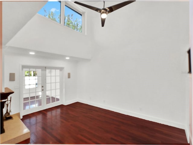 living room with dark wood-style floors, a high ceiling, ceiling fan, and baseboards