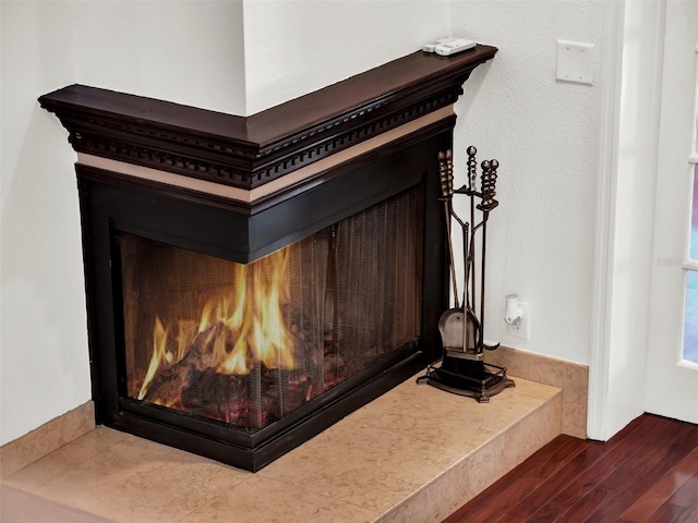 details featuring a warm lit fireplace and wood finished floors