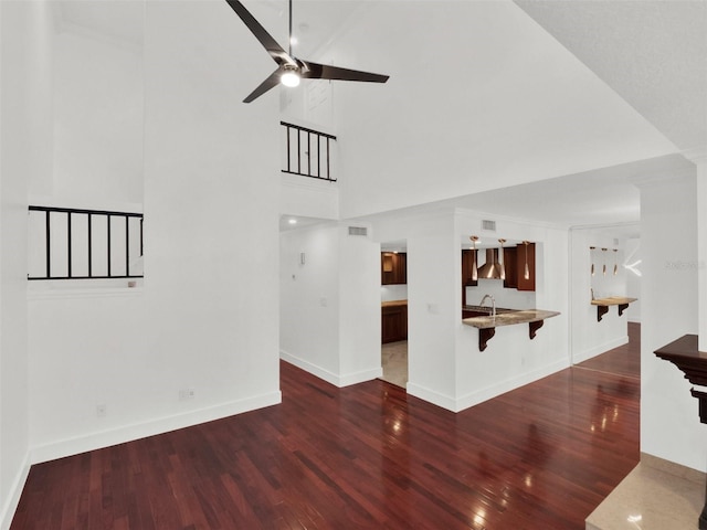 unfurnished living room featuring baseboards, visible vents, dark wood finished floors, and a ceiling fan